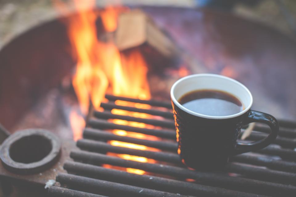 A black mug beside a warm outdoor fire